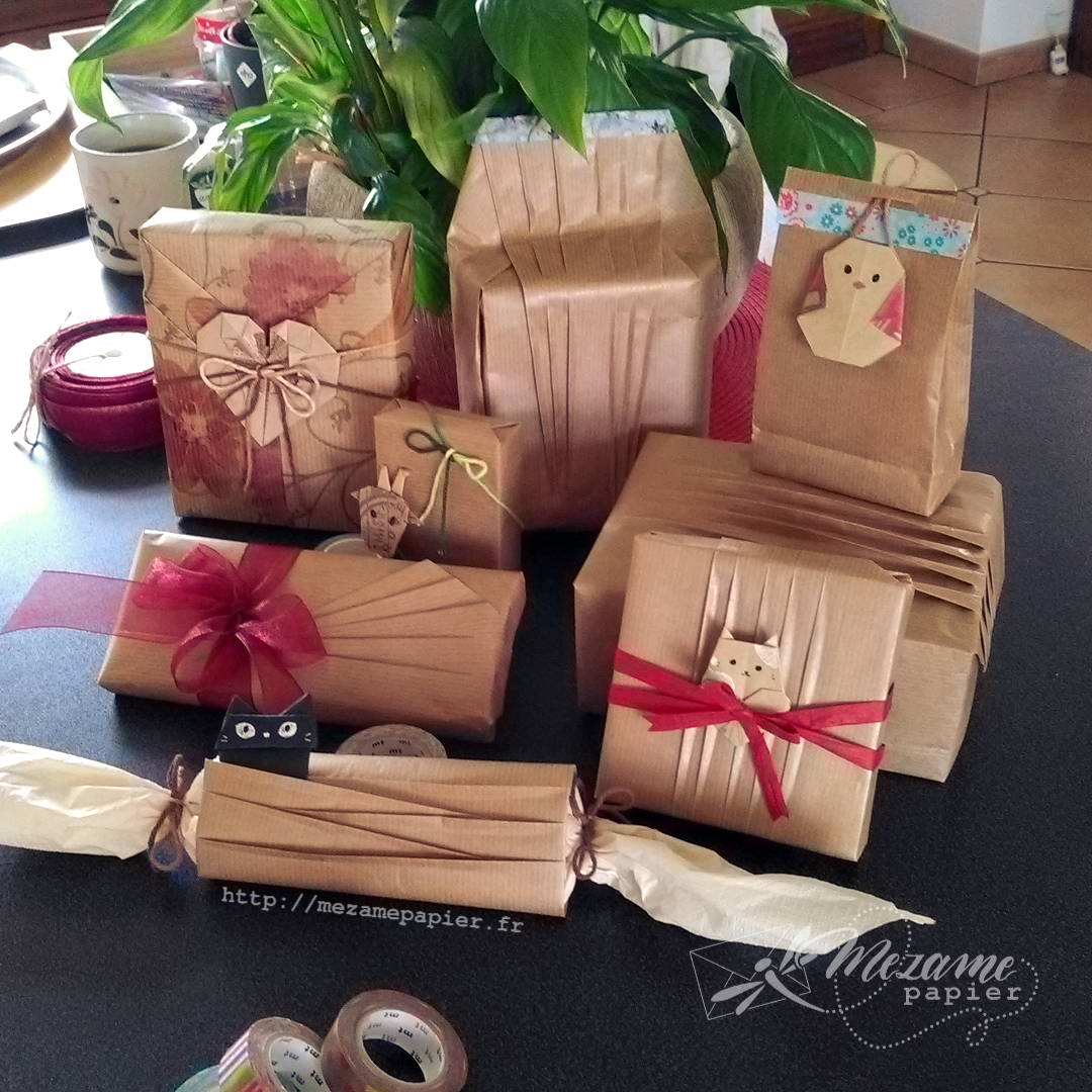 Pile de cadeaux emballés de papier kraft blond avec des plis élégants et des décorations en origami en forme de chats, selon des designs de Kamikey origami