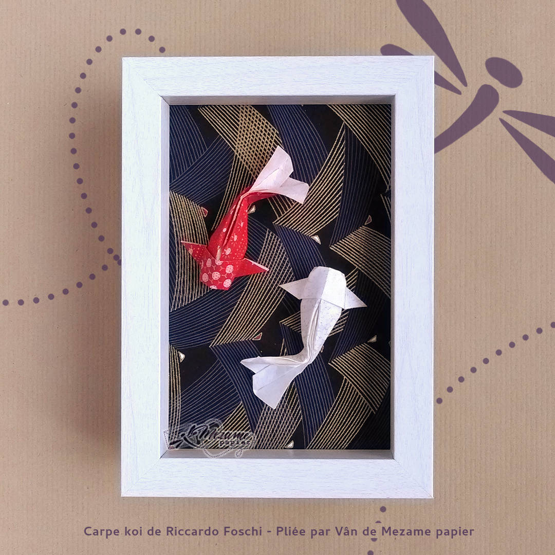 Cadre photo avec rebord blanc contenant un couple de carpes koi origami en papiers japonais nacrés, sur fond de papier japonais noir au motif d'épines de pin dorées graphiques